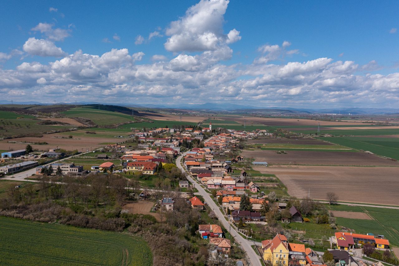 Aerial view of the rural village of Chanava in Slovakia, surrounded by fields under a bright blue sky.