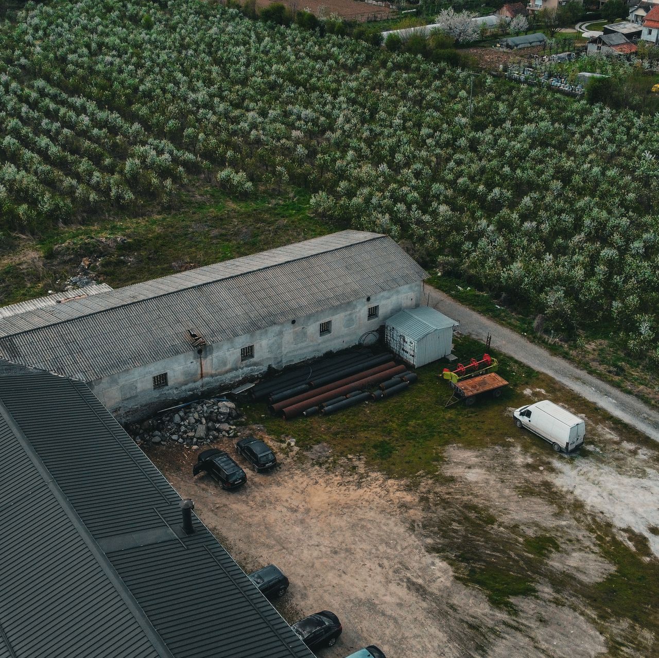 Drone shot capturing rural farm with buildings, fields, and equipment in a countryside setting.