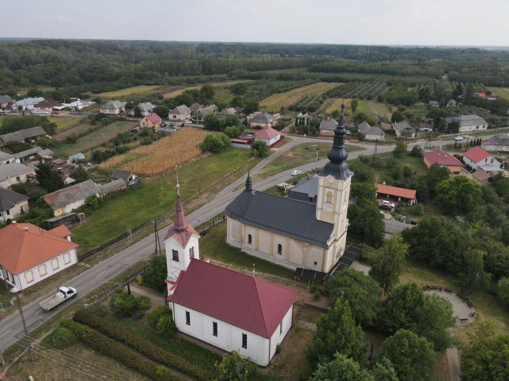 Aerial shot of Aranyosapáti, Hungary, showcasing two prominent churches amidst rural landscape.