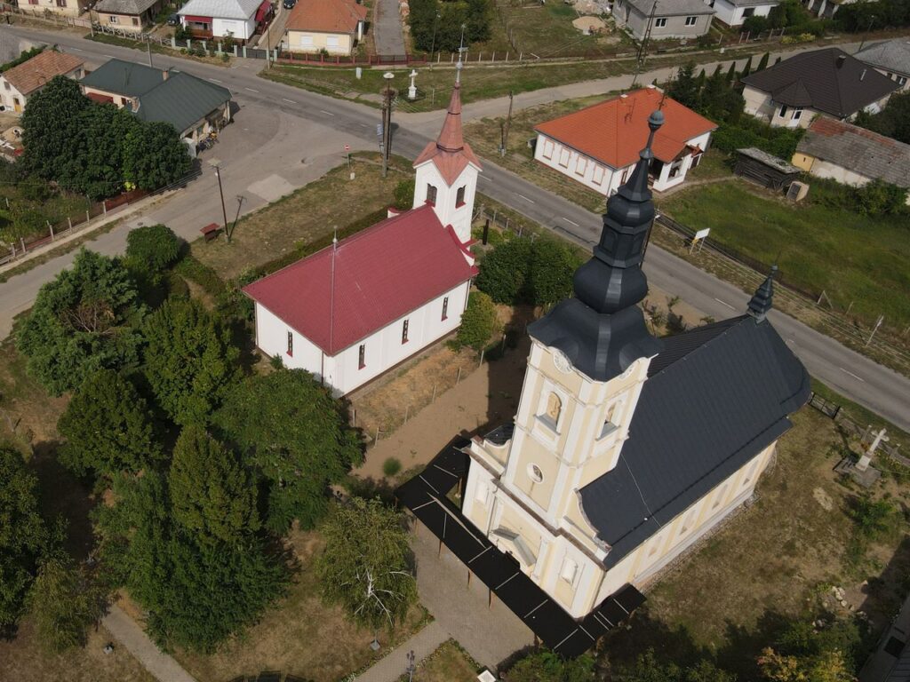 Drone shot of churches in Aranyosapáti, Hungary, showcasing architectural contrast.
